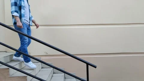 Young caucasian man walks down stairs from porch of building Видео 201496452