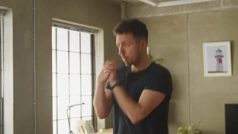 Young caucasian man warming up before exercising at home in living room Stock Footage 169014979