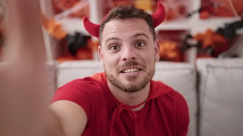 Young caucasian man wearing devil costume taking selfie picture at home Stock Footage 232871947