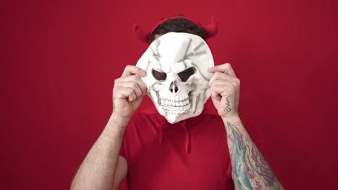Young caucasian man wearing devil costume covering face with skull over iso.. Stock Footage 238608039