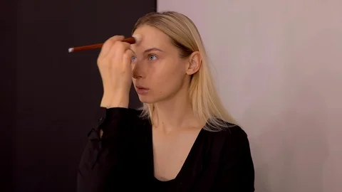 Young caucasian model applying professional makeup. beautiful woman applying Stock Footage 113864834