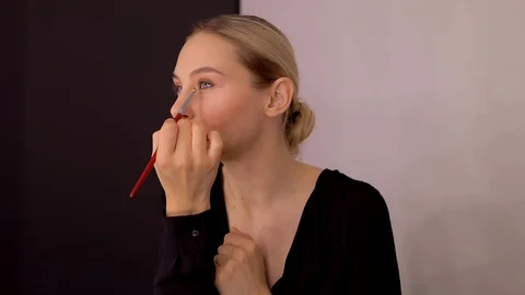 Young caucasian model applying professional makeup. beautiful woman applying Stock Footage 113868196