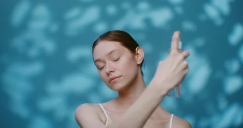 A young Caucasian model without makeup sprays liquid from a bottle on her face Stock Footage 168075138