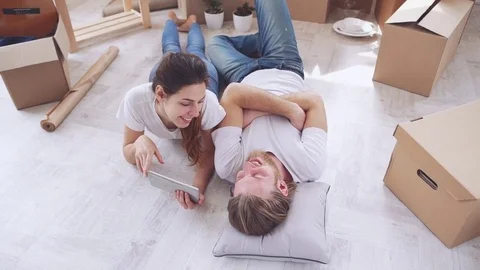 Young Caucasian pair lying on floor in their new flat in slowmotion. Concept of Stock Footage