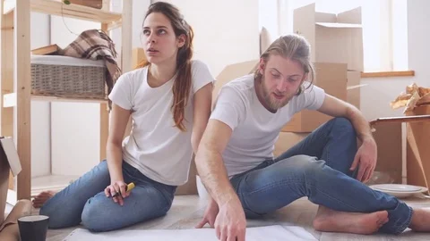 Young Caucasian pair planning furnishings in their new flat in slowmotion Stock Footage