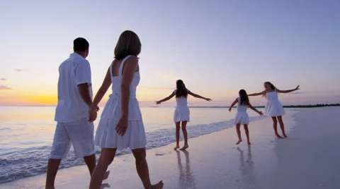 Young Caucasian parents and daughters on beach at sunrise Stock Footage