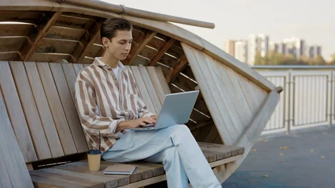 Young Caucasian Student is Sitting on the Bench and Studying on the Lap Top. It Stock Footage 237600717