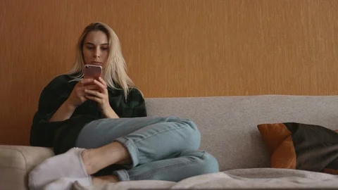Young caucasian student sitting at sofa use smartphone at loft social media 5g Stock Footage 113910833