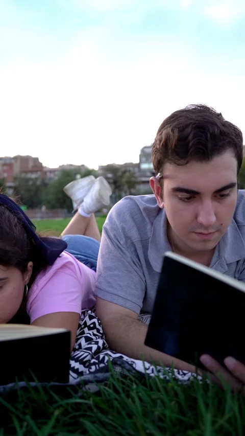 Young caucasian woman and man student friends relaxing, having fun, reading Stock Footage