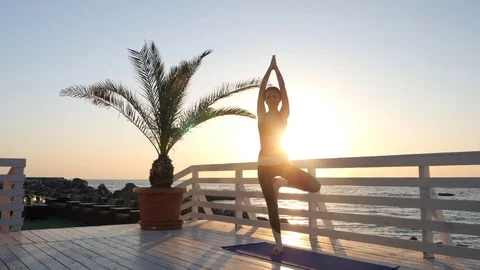 Young caucasian woman doing yoga asana in the nature on a wooden balcony over Stock Footage