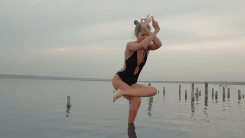 Young caucasian woman in swimsuit practicing yoga in water liman, lake or river Stock Footage