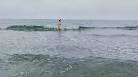 Young Caucasian woman walkin into the sea Stock Footage