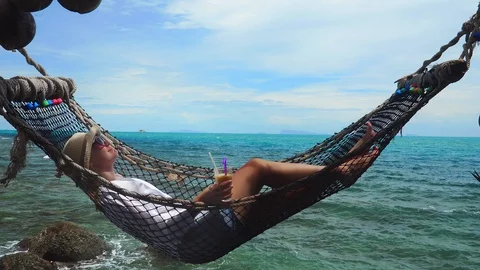 Young Caucasian WomanDrinking Mango Shake Beverage in Hammock Beside Turquoise Stock Footage 111710154