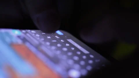Young caucasian worker typing on his phone in a dark bakground. phone texting Stock-Footage 201409329