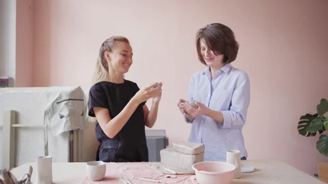 Young ceramic teacher and mature student talking while wedging clay Stock Footage 106830053