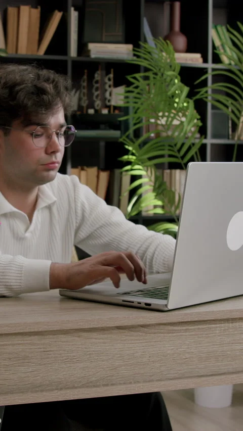 Young chalky boy with glasses is typing on a computer working on an important Stock Footage 316604150