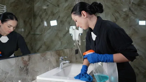 Young chambermaid cleaning tap in bathroom Video stock 273130341