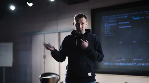 A young charismatic man makes a presentation in a dark auditorium. The speaker Stock Footage 199224092