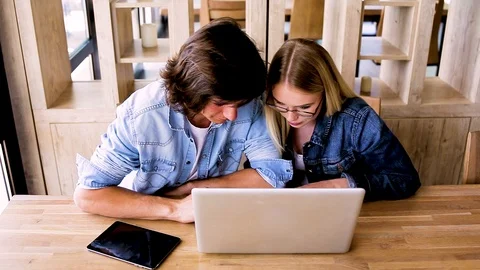 Young charming couple using laptop while sitting at cafe Stock Footage 89826834