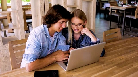 Young charming couple using laptop while sitting at cafe Stock Footage 89827434
