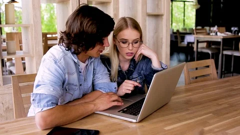 Young charming couple using laptop while sitting at cafe Video stock 89827436