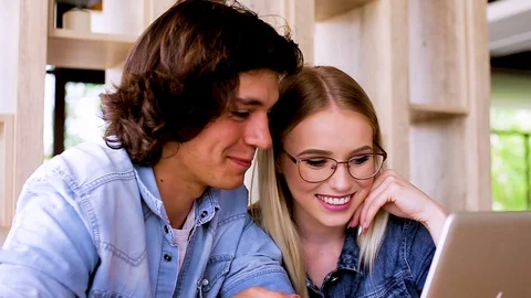 Young charming couple using laptop while sitting at cafe Stock Footage 89827646