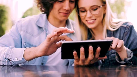Young charming couple using tablet while sitting side by side Video stock 89826389