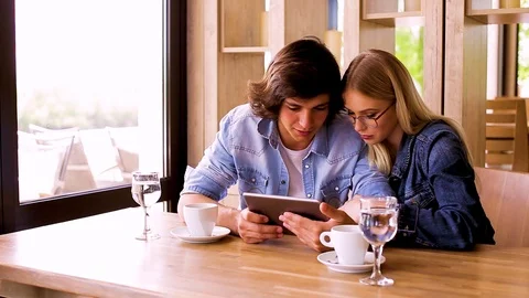 Young Charming Couple Using Tablet While Sitting Together And Drinking Coffee Stock Footage 89828005
