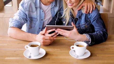 Young Charming Couple Using Tablet While Sitting Together And Drinking Coffee Stock Footage 89828649