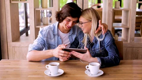 Young Charming Couple Using Tablet While Sitting Together And Drinking Coffee Video stock 89829050