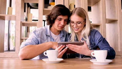 Young Charming Couple Using Tablet While Sitting Together And Drinking Coffee Stock Footage 89829138