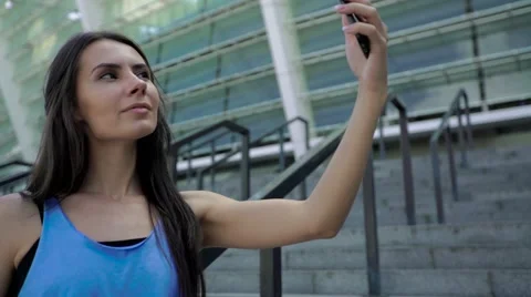 Young charming female runner is having break and taking selfie standing on Stock Footage 65380682