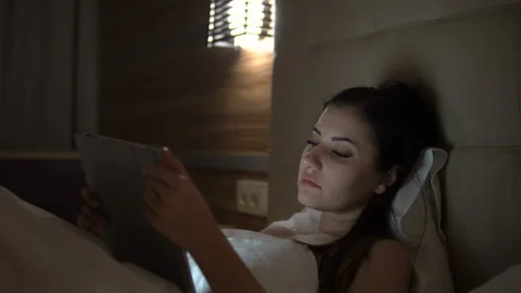 Young charming girl are using digital tablet on the bed before she sleeping at Stock Footage 88181717