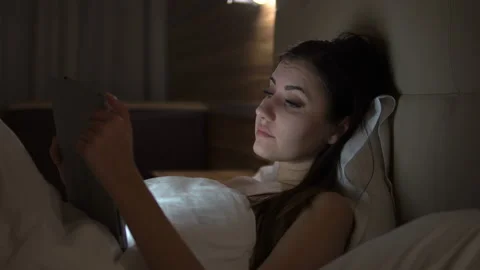 Young charming girl are using digital tablet on the bed before she sleeping at Stock Footage 88183663
