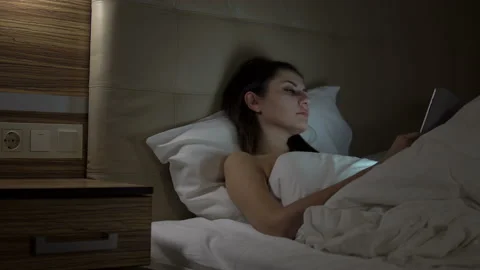 Young charming girl are using digital tablet on the bed before she sleeping at Stock Footage 88888262