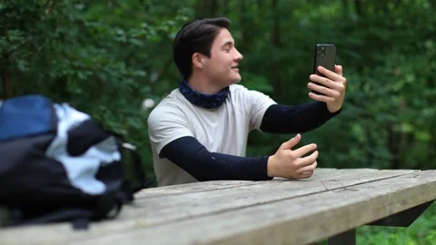 Young cheerful active guy in the forest making a video call shows his finger 動画素材 252390912