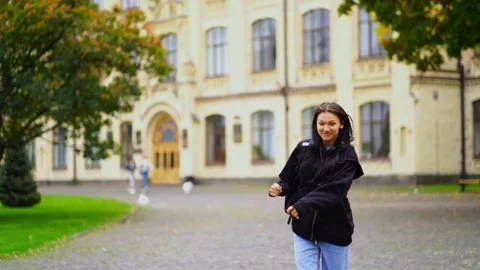 Young cheerful brunette student jumping near campus in slow motion Stock Footage 296069874