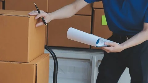 Young cheerful delivery man with parcel near car full of cardboard boxes, f.. Stock Footage 278839659