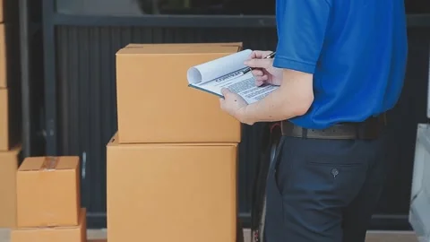 Young cheerful delivery man with parcel near car full of cardboard boxes, f.. Stock Footage 278839676