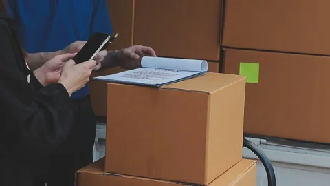 Young cheerful delivery man with parcel near car full of cardboard boxes, f.. Stock Footage 278839681