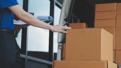 Young cheerful delivery man with parcel near car full of cardboard boxes, f.. Stock Footage 278839692