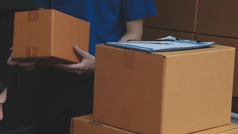 Young cheerful delivery man with parcel near car full of cardboard boxes, f.. Stock Footage 278839728