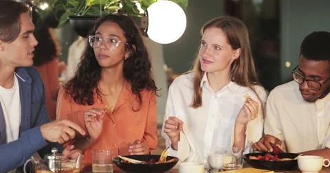 Young cheerful friends having fun and laughing while eating in modern cafe Stock Footage 135572939