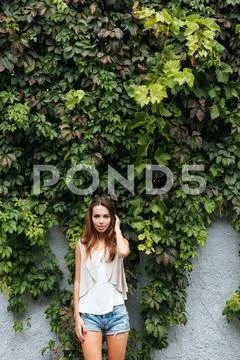 Young cheerful girl posing outdoors with green leaves background Stock Photos