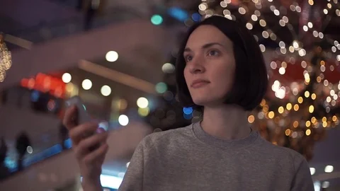 Young cheerful girl smiling using smartphone in shopping mall. Stock Footage 83367908