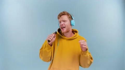 Young Cheerful guy with red curly hair 20s dances with headphones listening to Stock Footage 234901267