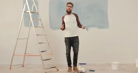 Young cheerful handsome caucasian guy stands on background of unpainted wall Stock Footage 147059929