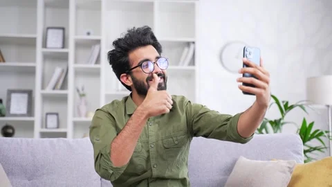 Young cheerful handsome man talking on a video call holding a smartphone while  Stock Footage 252200819