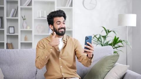 Young cheerful handsome man talking on a video call holding a smartphone while  Stock Footage 252205619