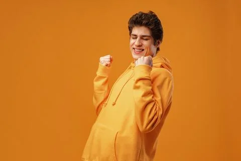 Young cheerful man dancing having fun over yellow background Foto stock